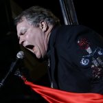 Performer Meat Loaf sings into a microphone and waves a red cloth
