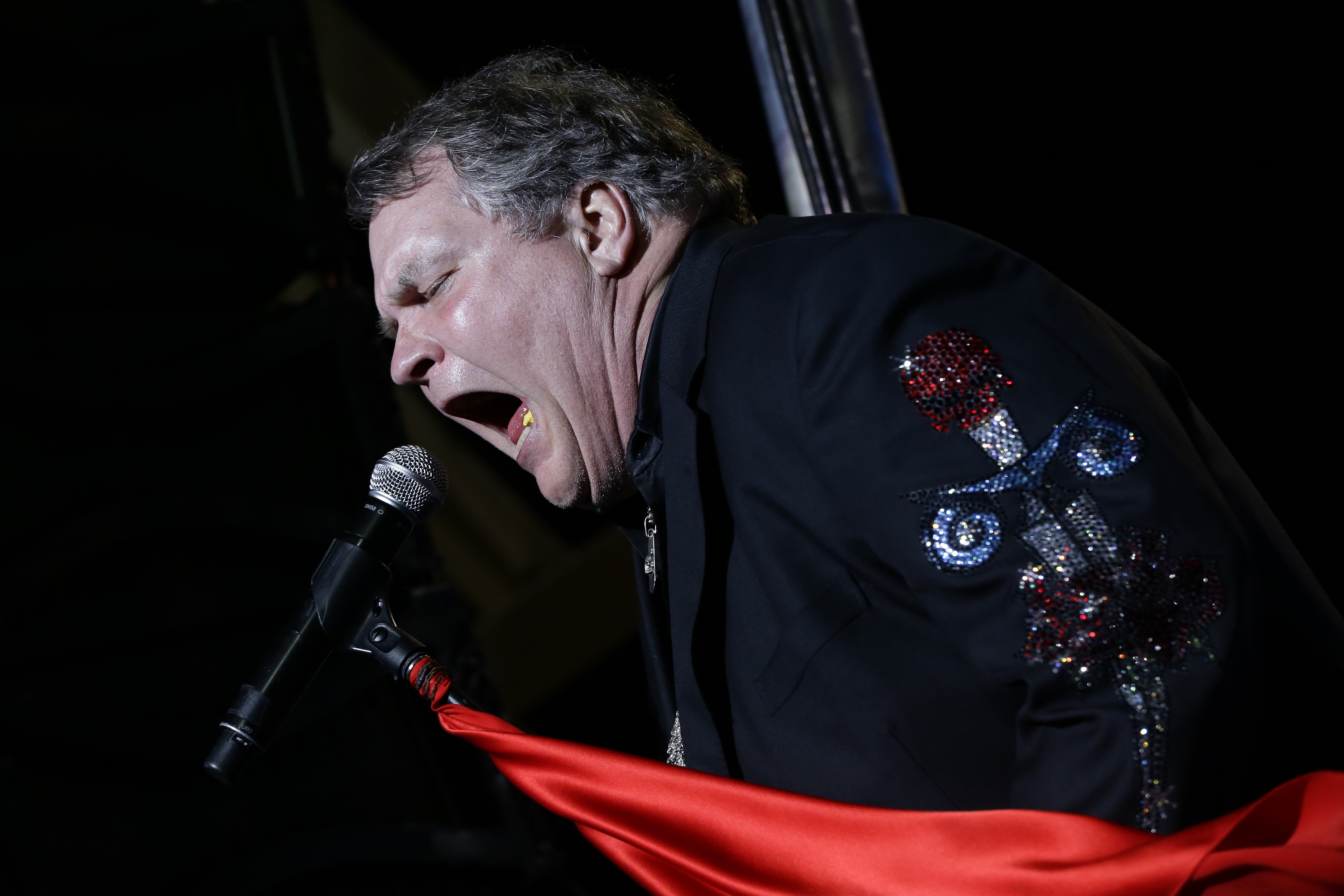 Performer Meat Loaf sings into a microphone and waves a red cloth