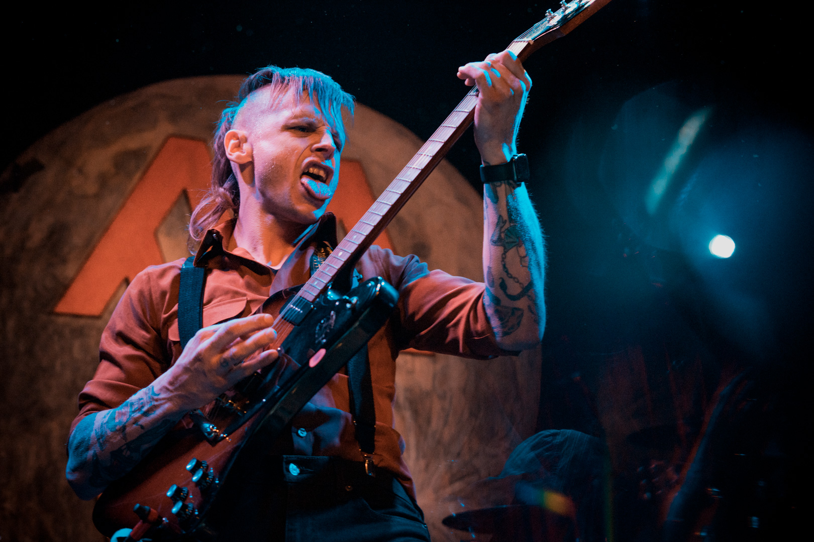 A man plays guitar with his tongue out on stage
