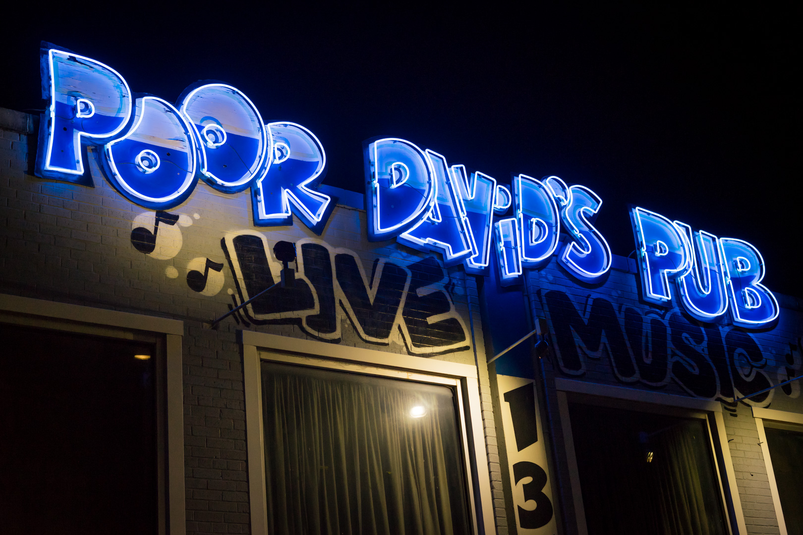 A front face of a venue with neon sign "Poor David's Pub"