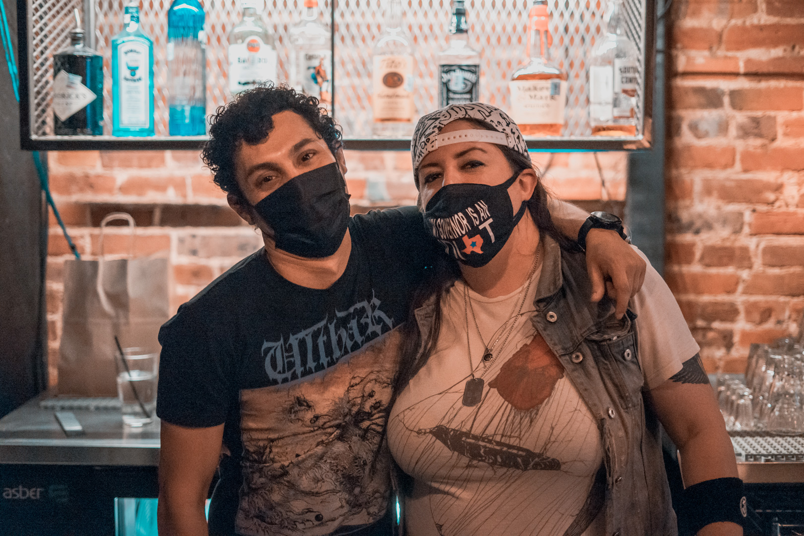 A man ad woman in face masks hug and smile