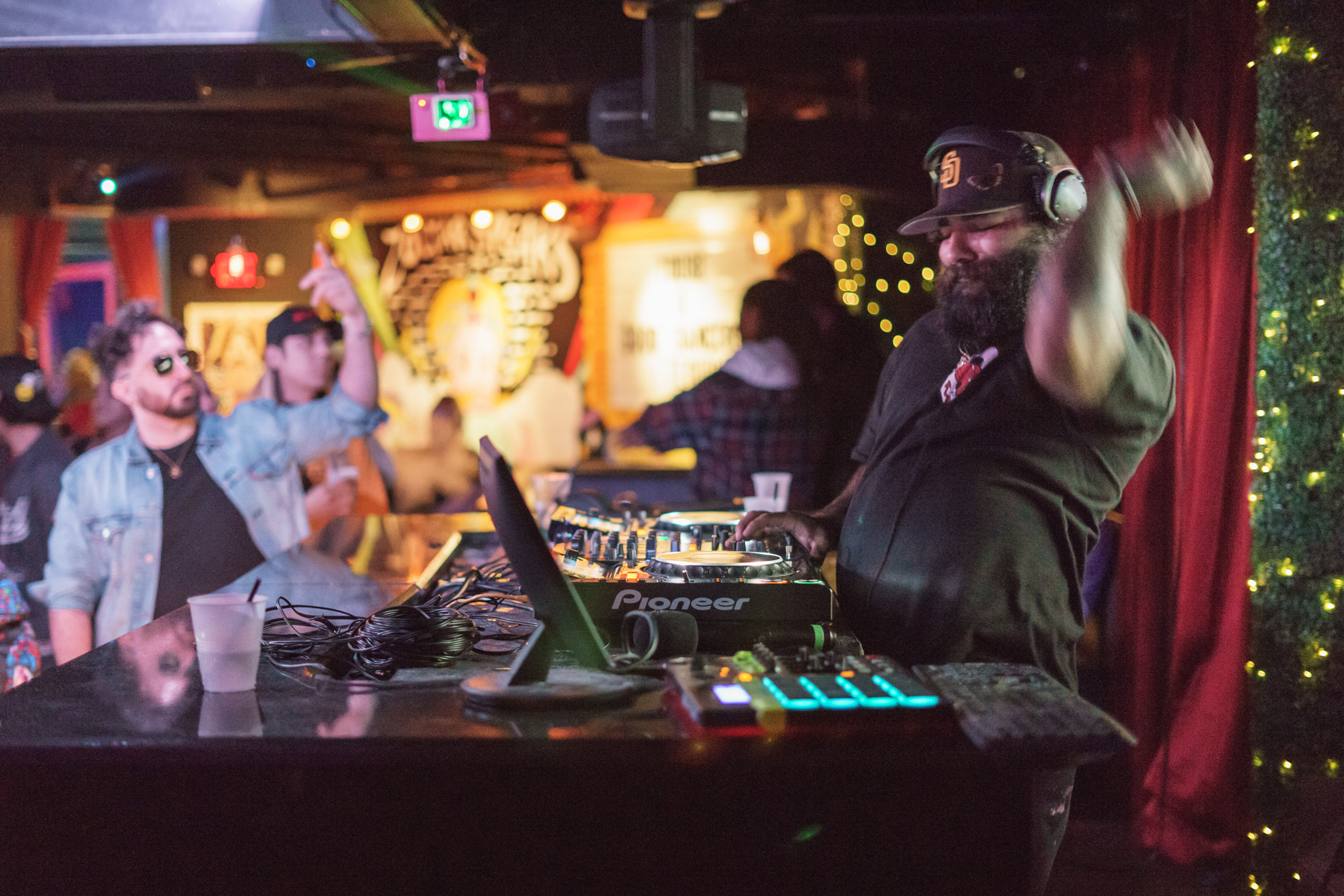 A dj spins the turntables while a party goer has his arm up in front