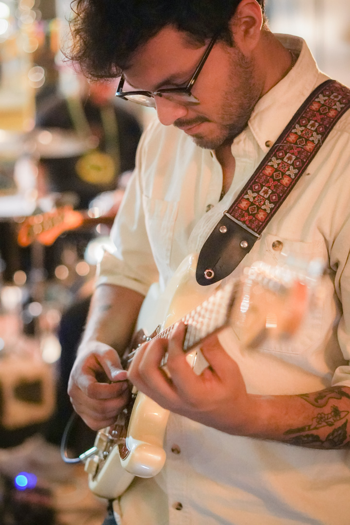 A young man plays a white electric guitar