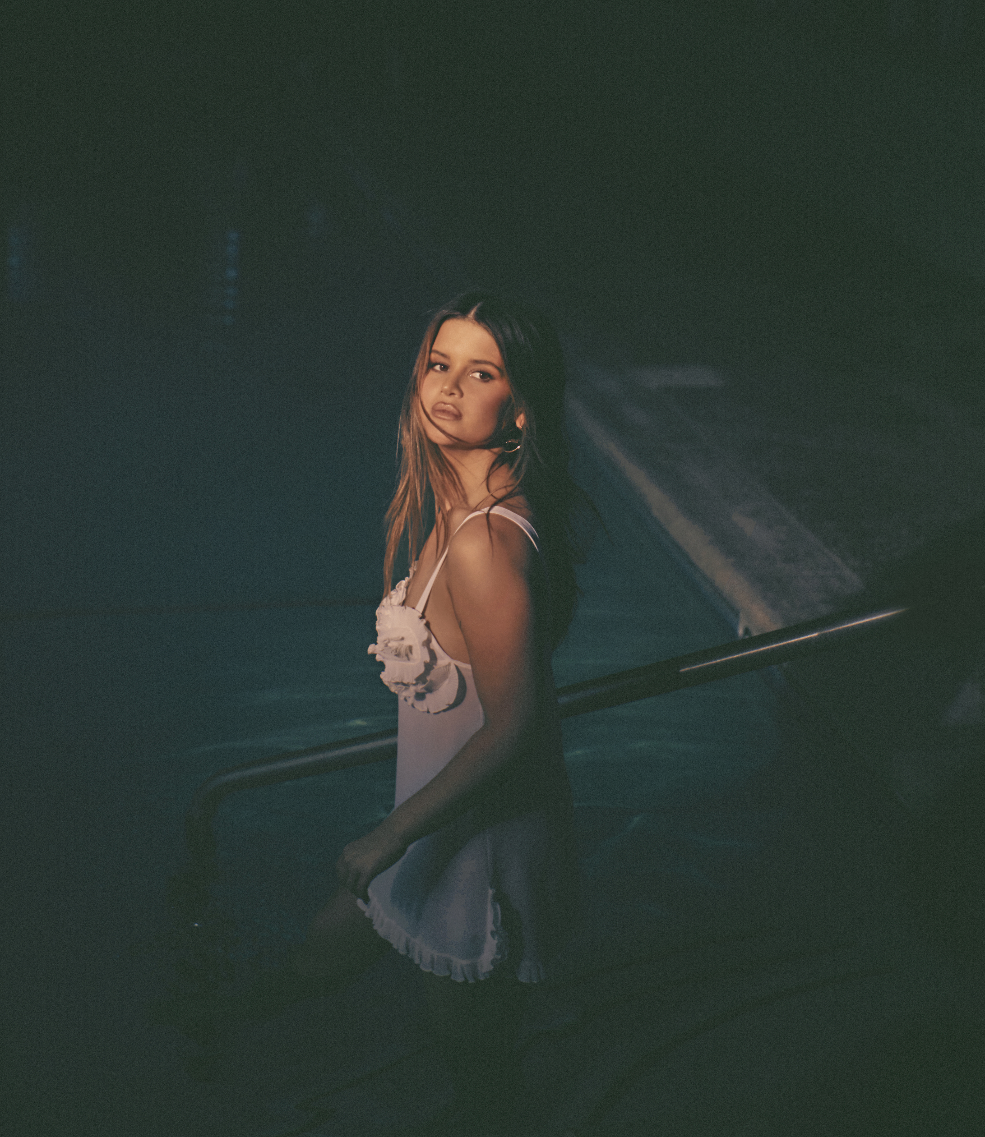 Maren Morris, wearing a white dress, descends into a swimming pool