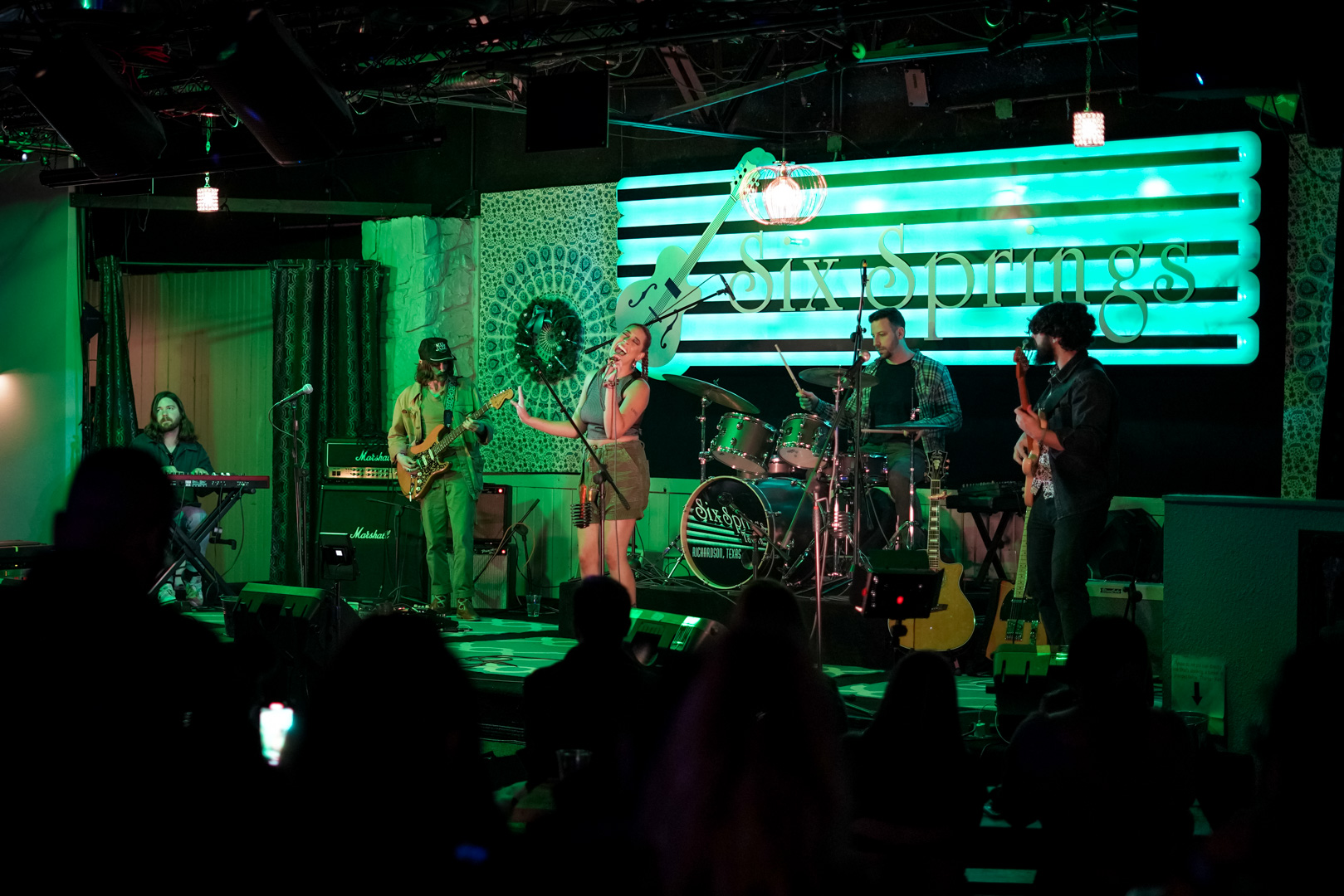 a full band with 5 musicians plays on stage - keys, guitar, vocals, drums, bass