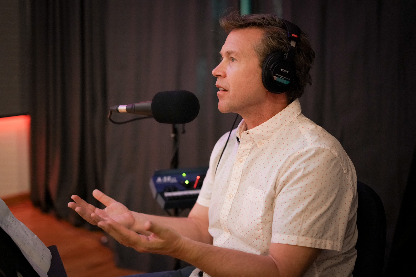 A man sits in front of a microphone while speaking