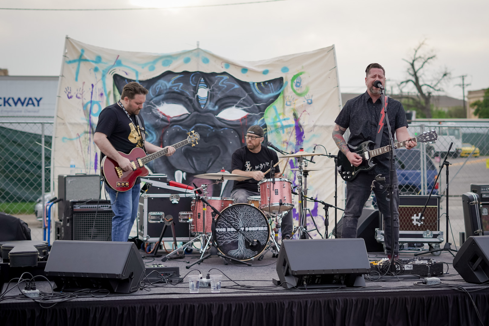 A 3-piece band plays on an outdoor stage in front of painted panther mural