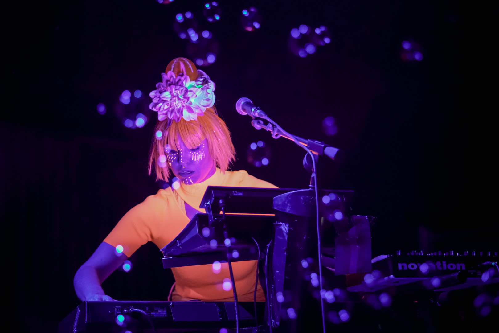 A woman in neon orange outfit plays keys 