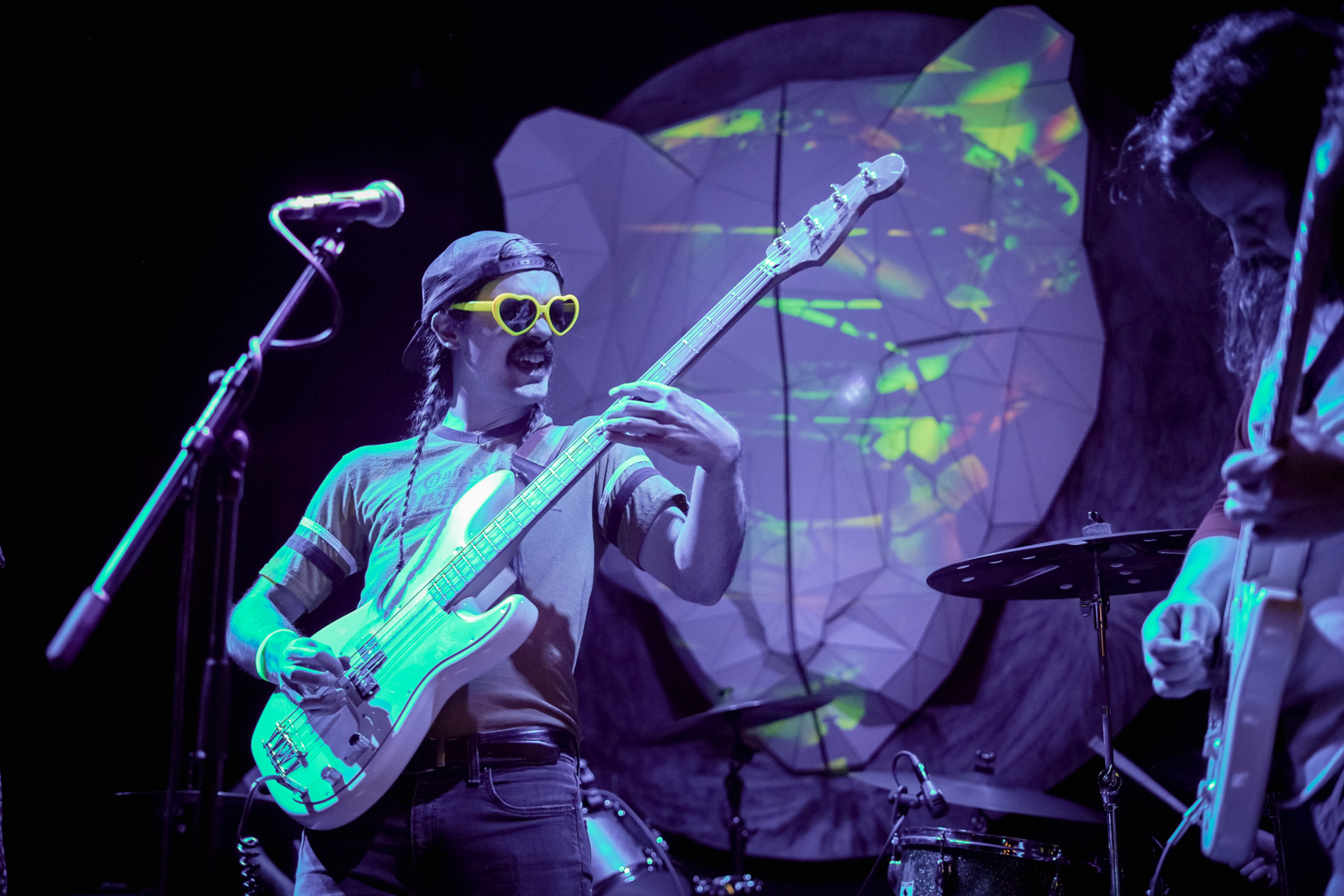 A man plays guitar while wearing heart-shaped glowing sunglasses