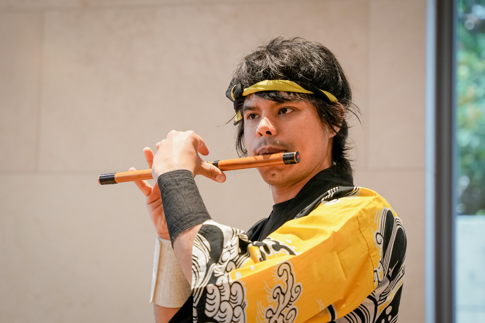 A young man plays a wooden flute