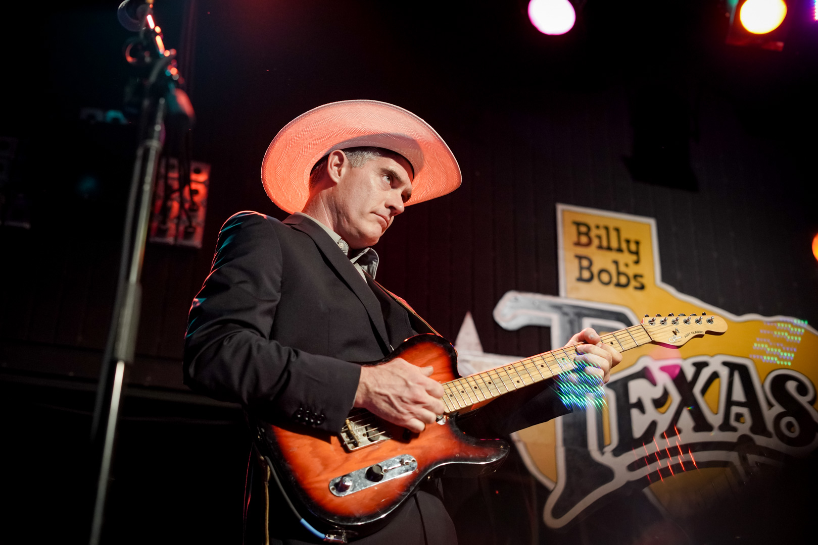 A guitar player on stage wearing cowboy hat