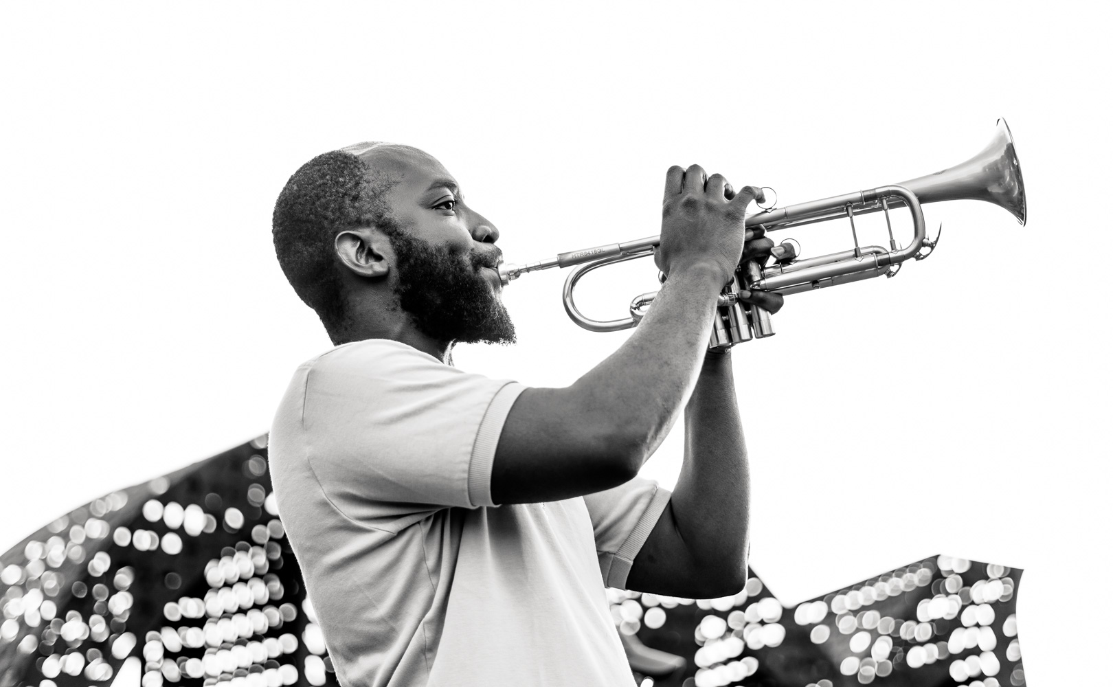 A man plays trumpet in a black and white photo