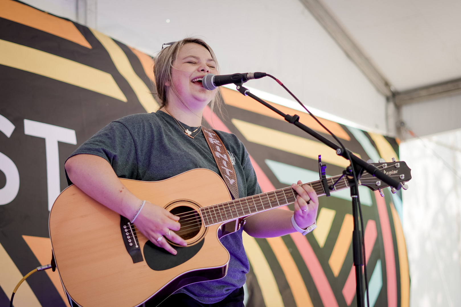 A young woman plays acoustic guitaron stage