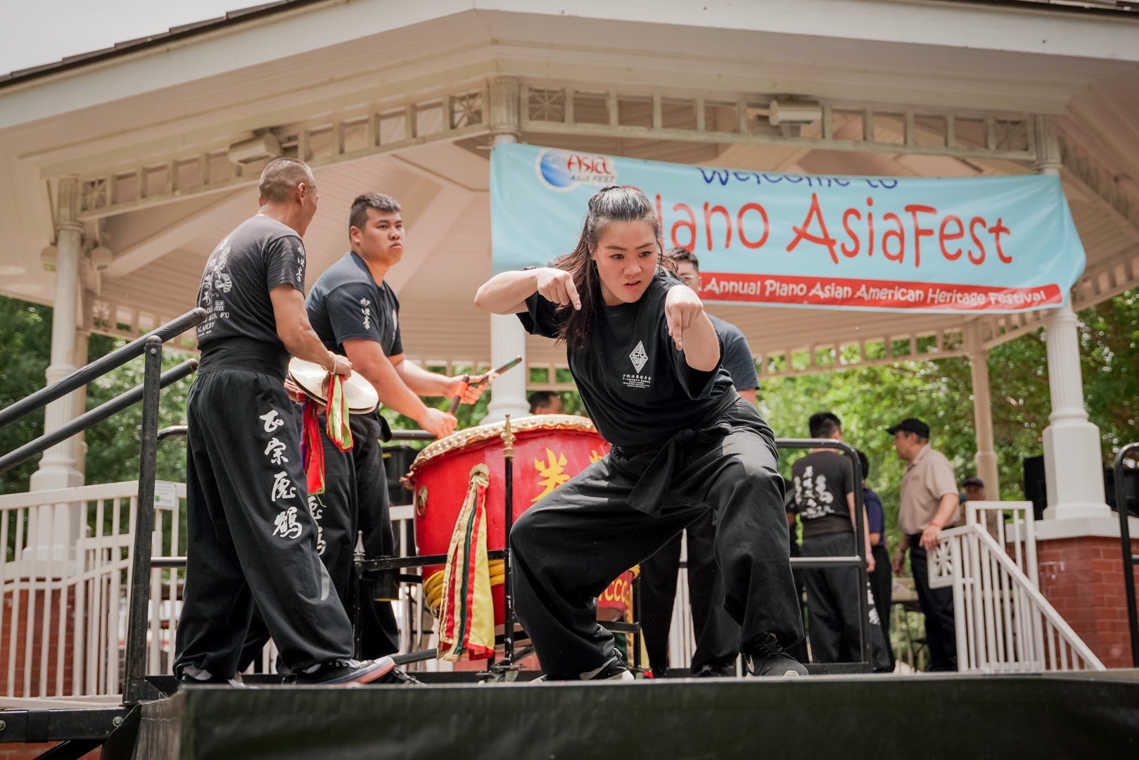 A woman performs Chinese Kung Fu in front of a small group of percussionists with a large drum and cymbals