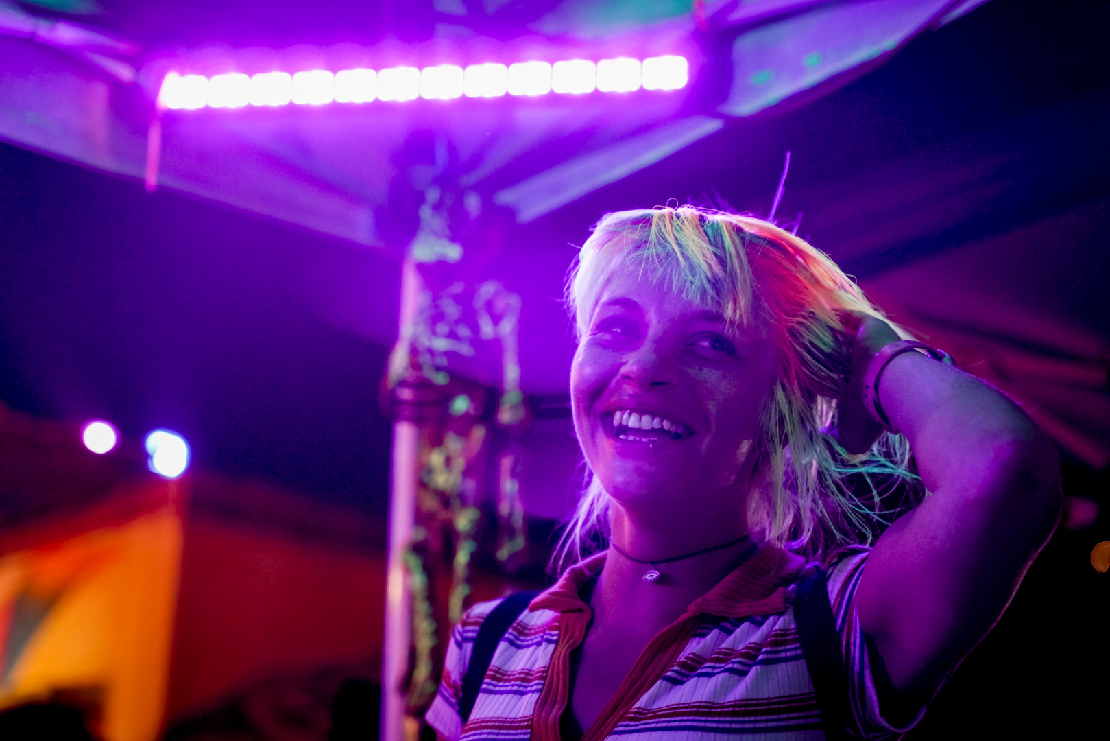 A woman smiling with neon hair under blacklight