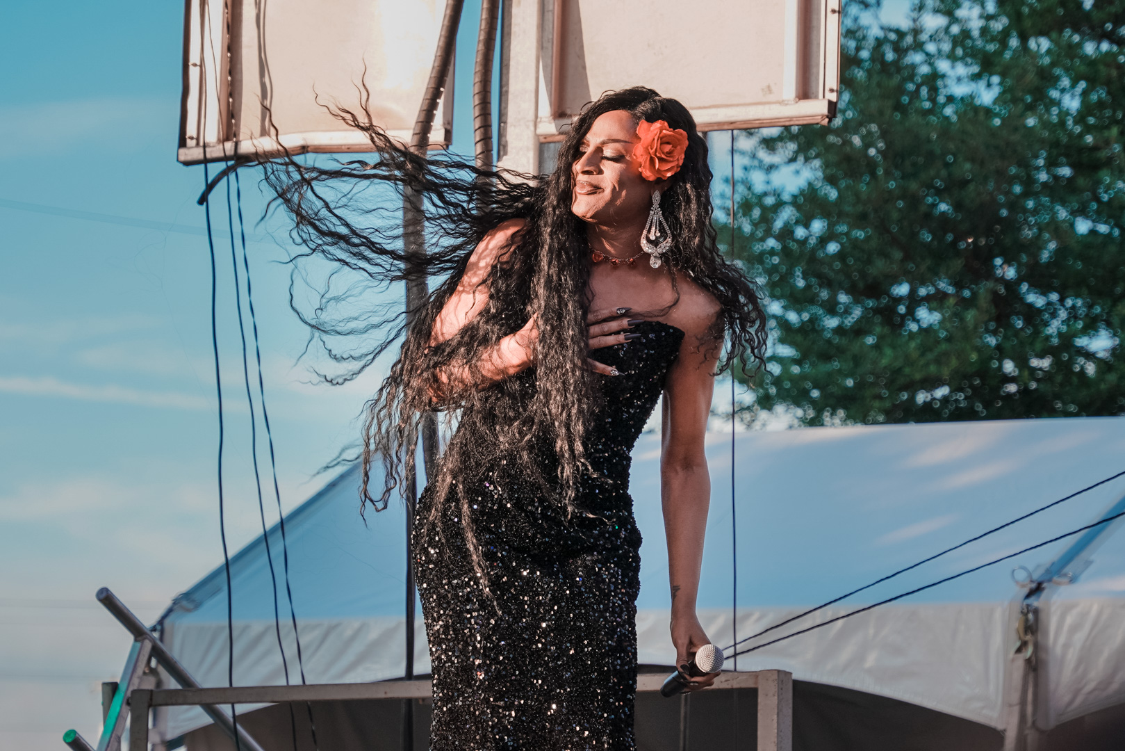 A performer on stage smiling with long hair blowing in the wind