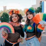 Two people in colorful rainbow outfits