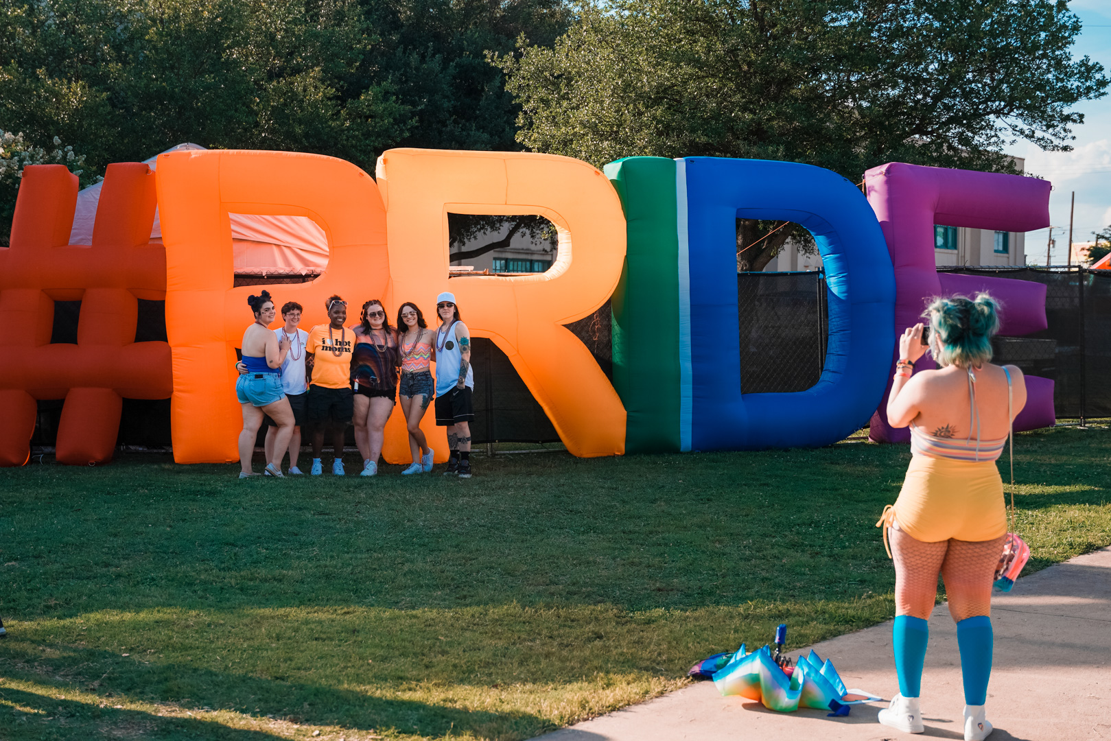 A group of friends standing in front of inflated letters that spell "#PRIDE" 