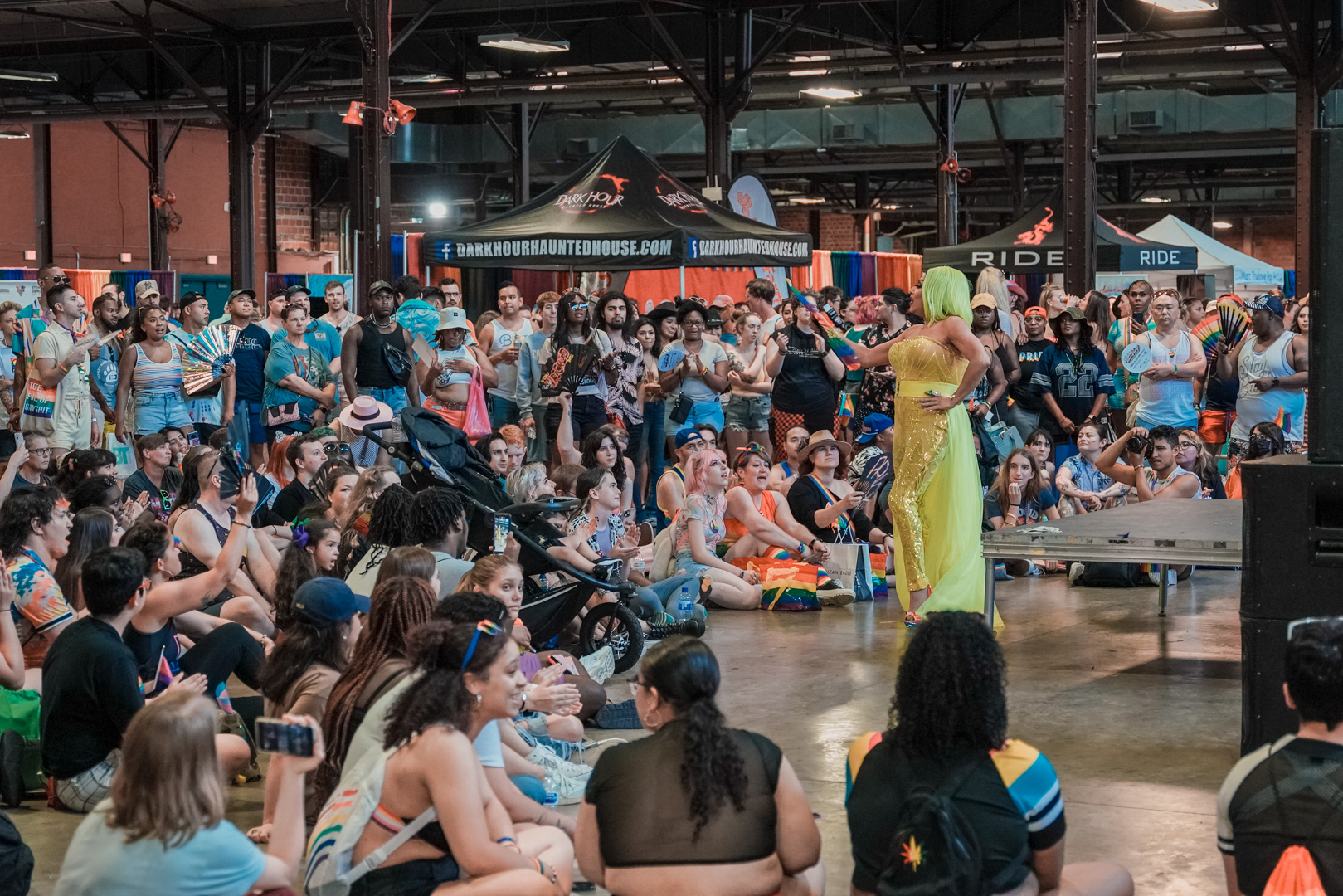 A performer in drag in front od a large seated crowd