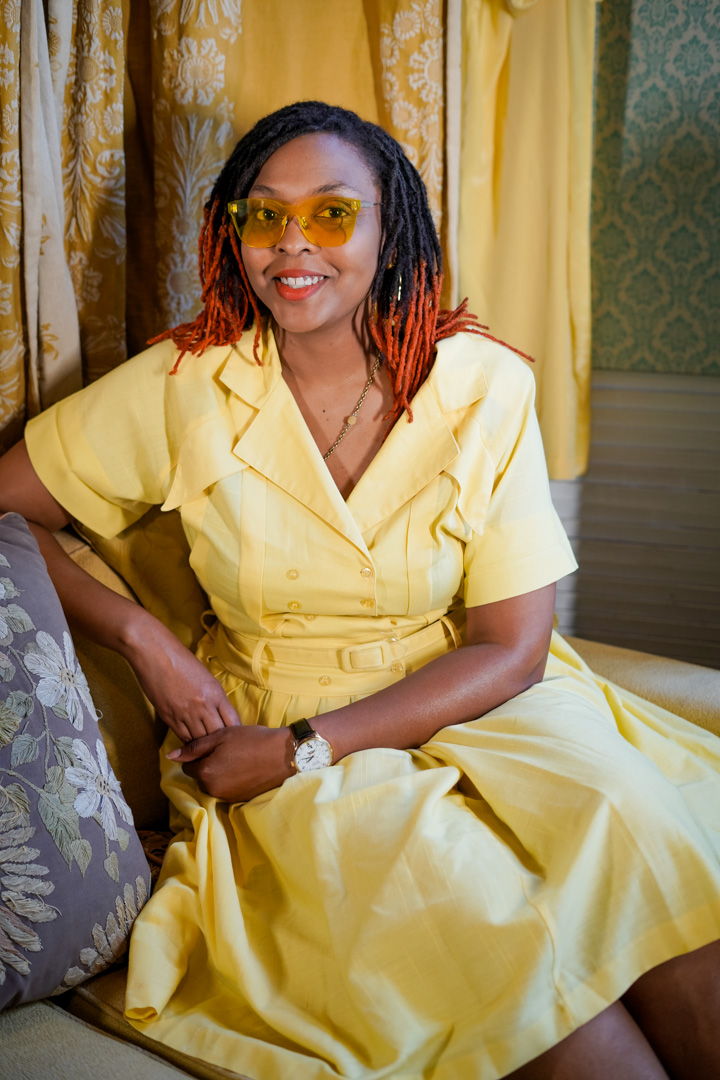 A woman sits smiling in a yellow dress