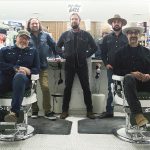 The band Left Arm Tan stands and sits inside a barbershop, facing the camera