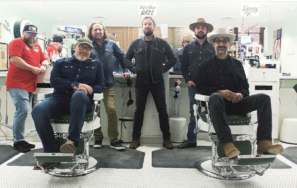 The band Left Arm Tan stands and sits inside a barbershop, facing the camera