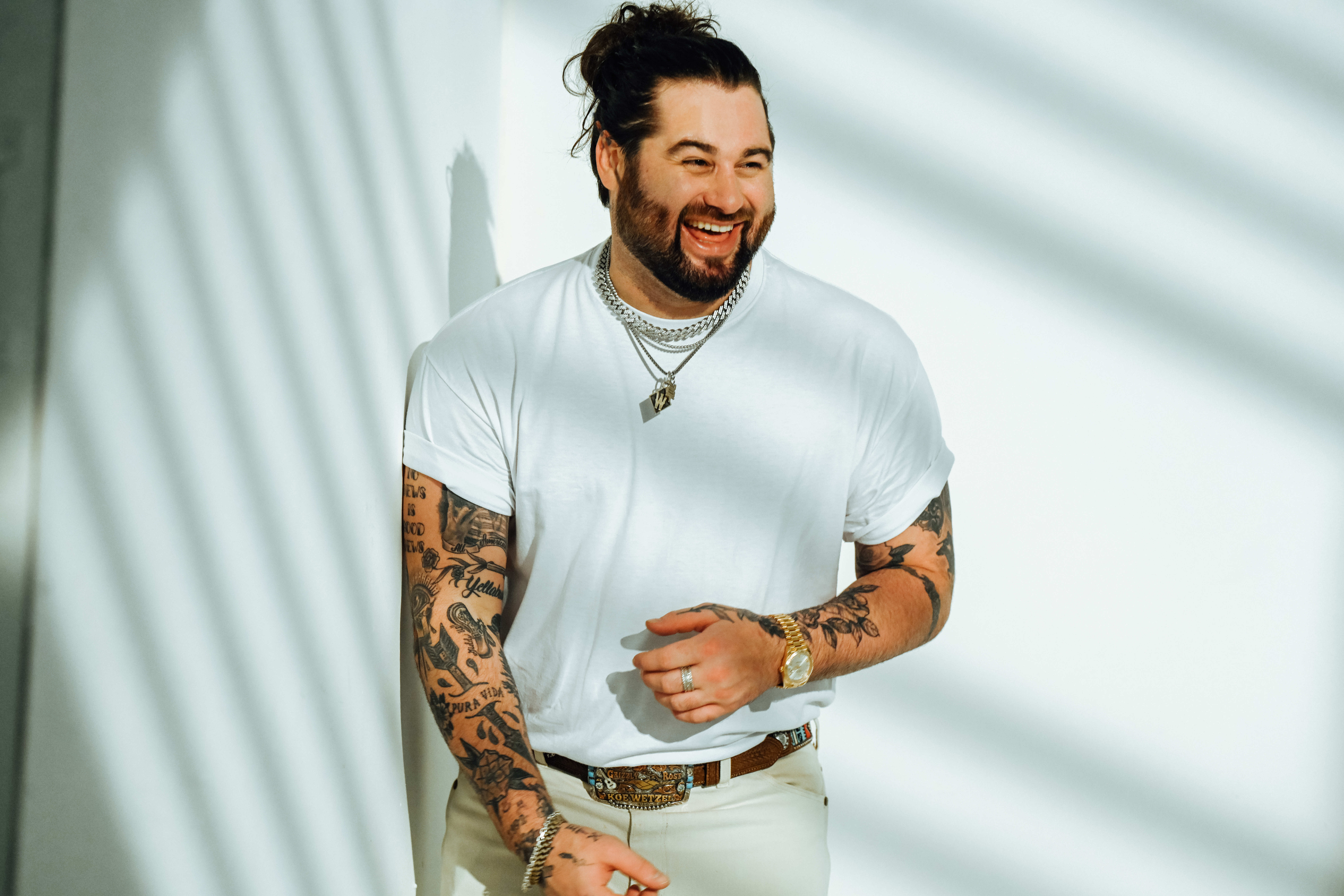 Wearing all white, Koe Wetzel smiles at the camera