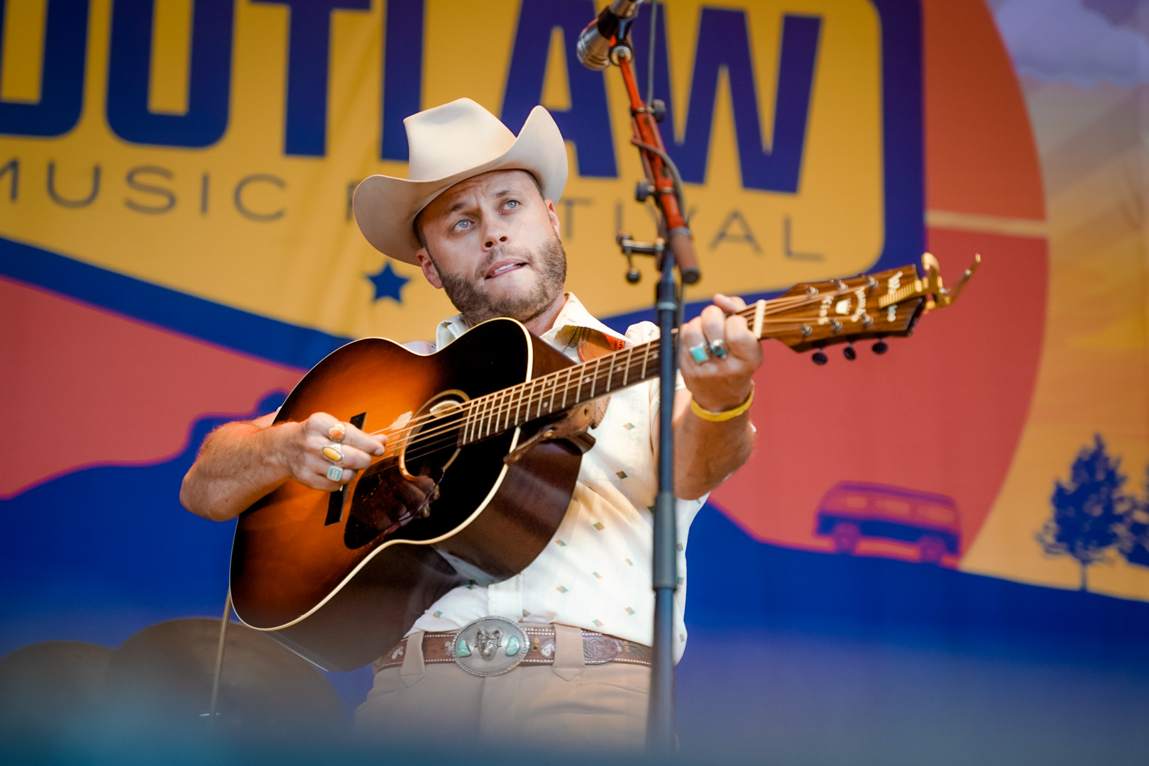 A handsome man in a cowboy hat plays guitar