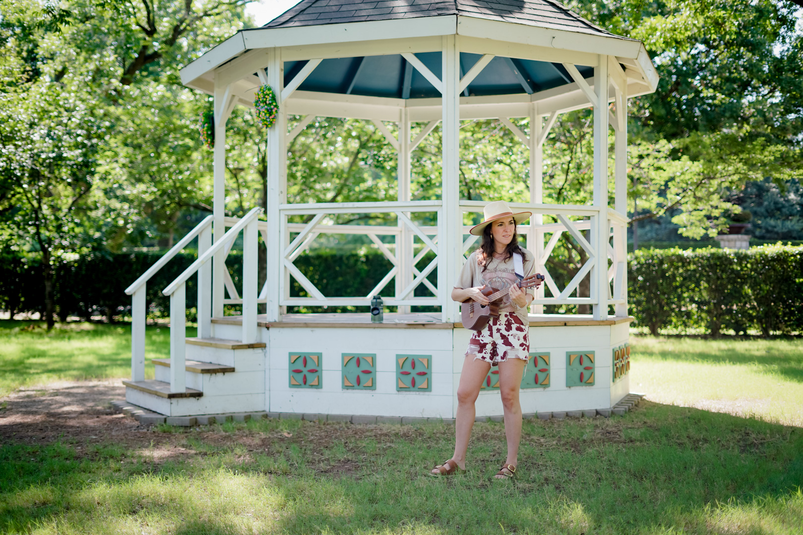 A woman playing ukulele in front of a gazebo 