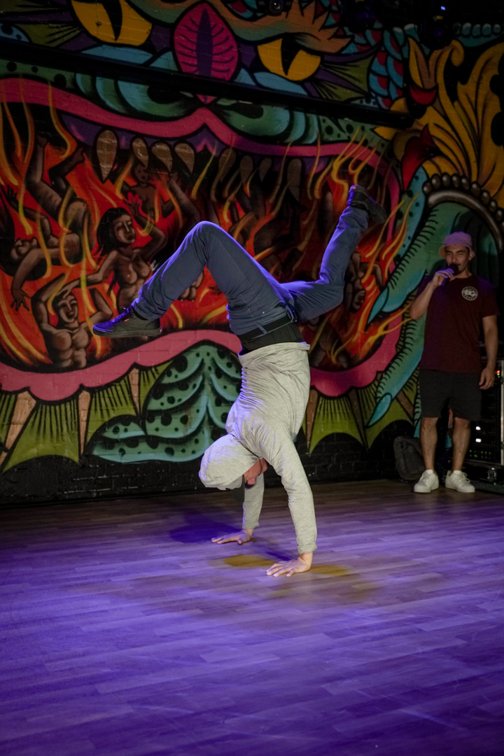 A performer on stage in a break dance move upside down standing on their hands