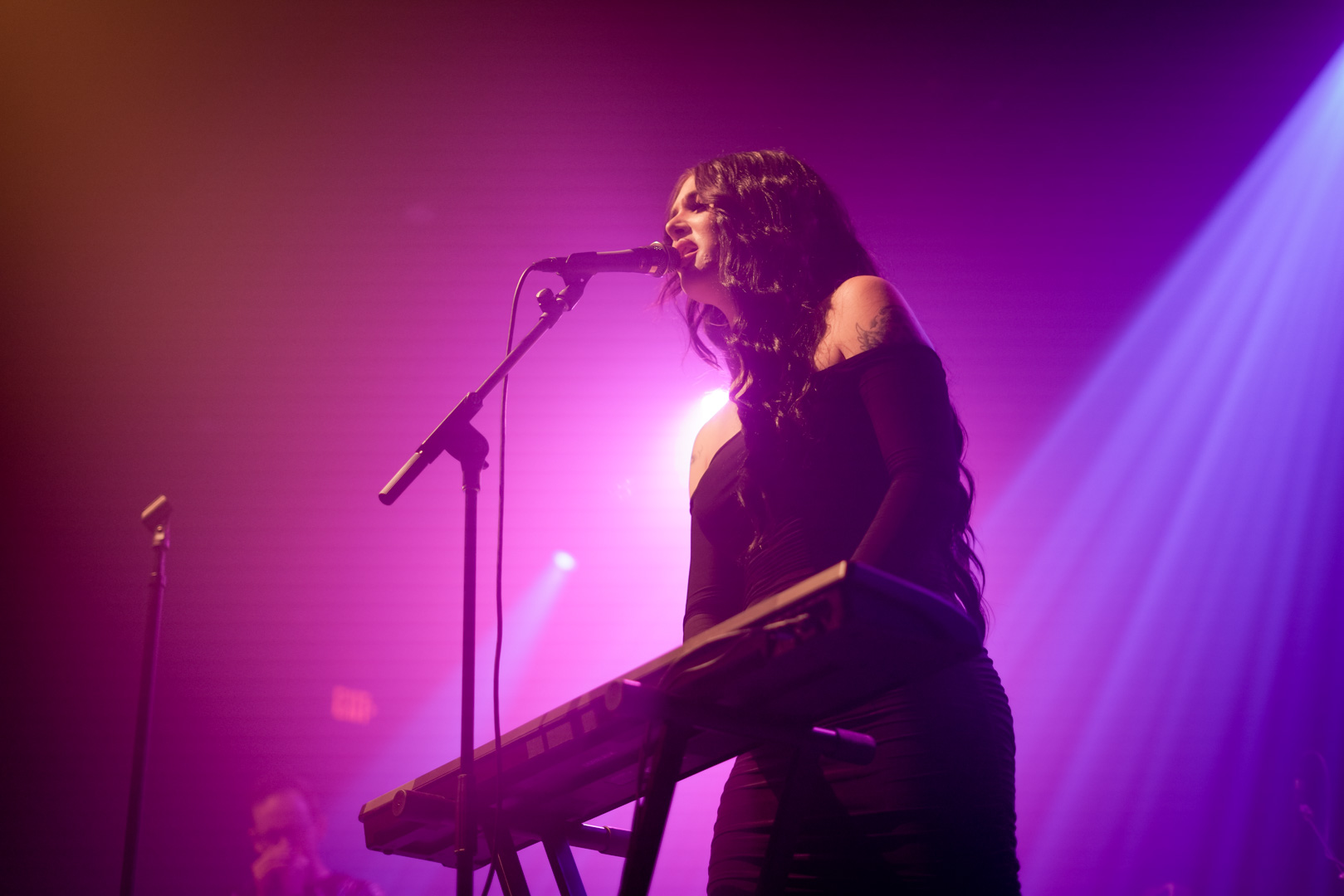 A woman plays keyboard and sings on stage