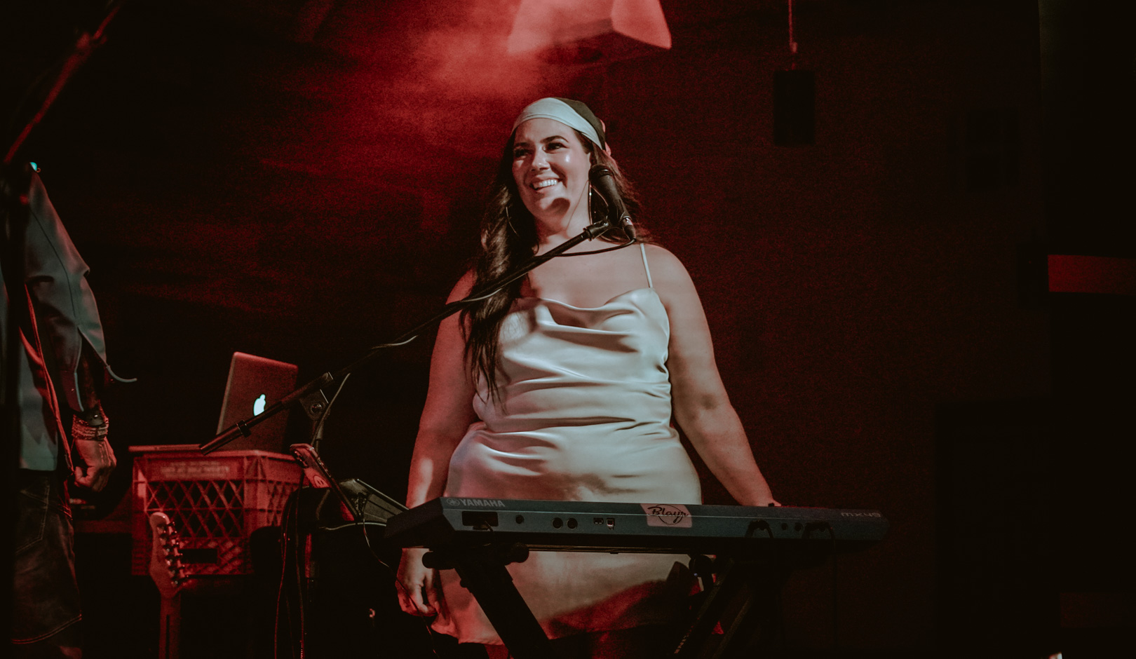 A woman smiling on stage behind a keyboard