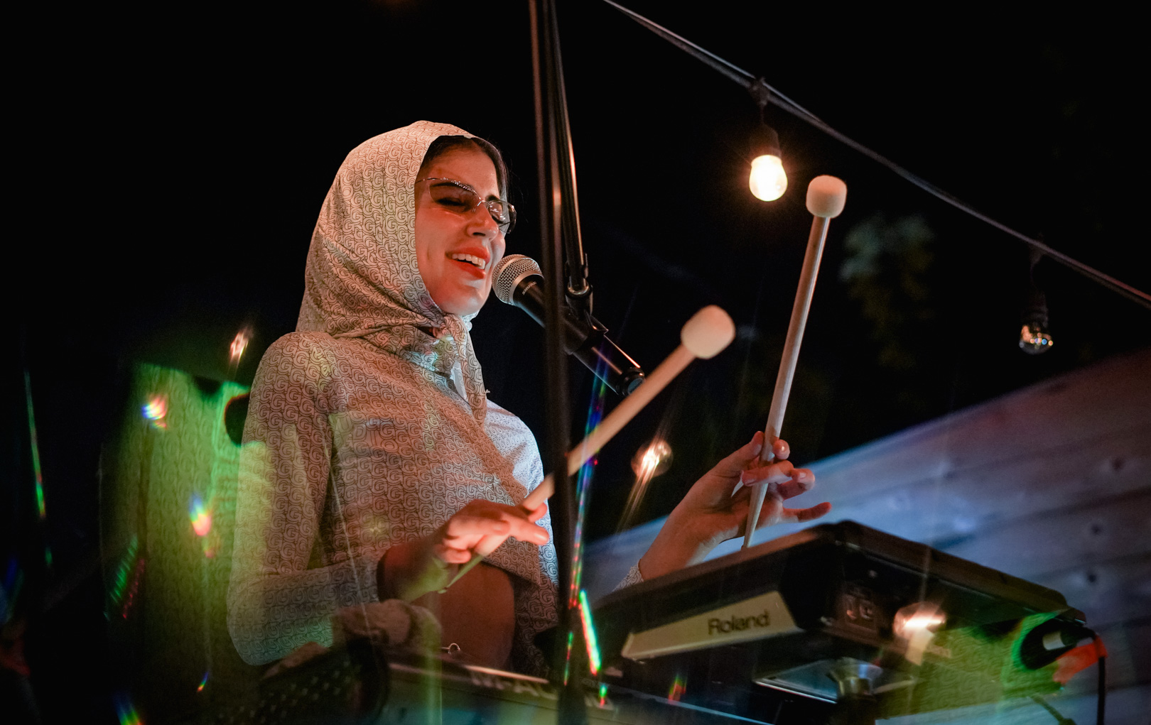 A woman singing and playing with percussion mallets on stage