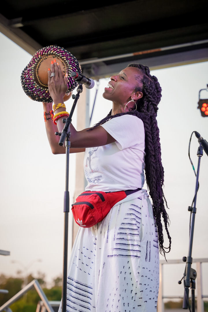 A woman playing a gourd shekere on stage