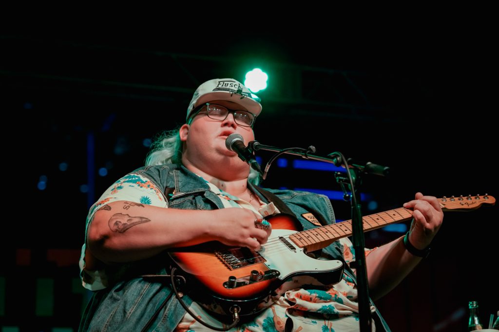 A man singing on stage while playing guitar