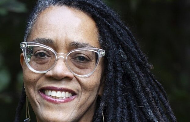 Author Francesca Royster, wearing glasses, smiles facing the camera