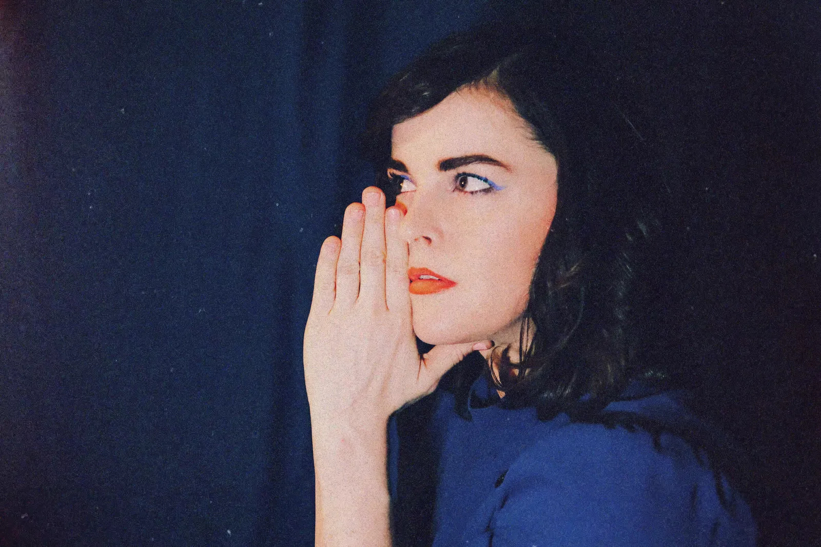 Tiffiny Costello, with a hand raised to her face, looks off to the left