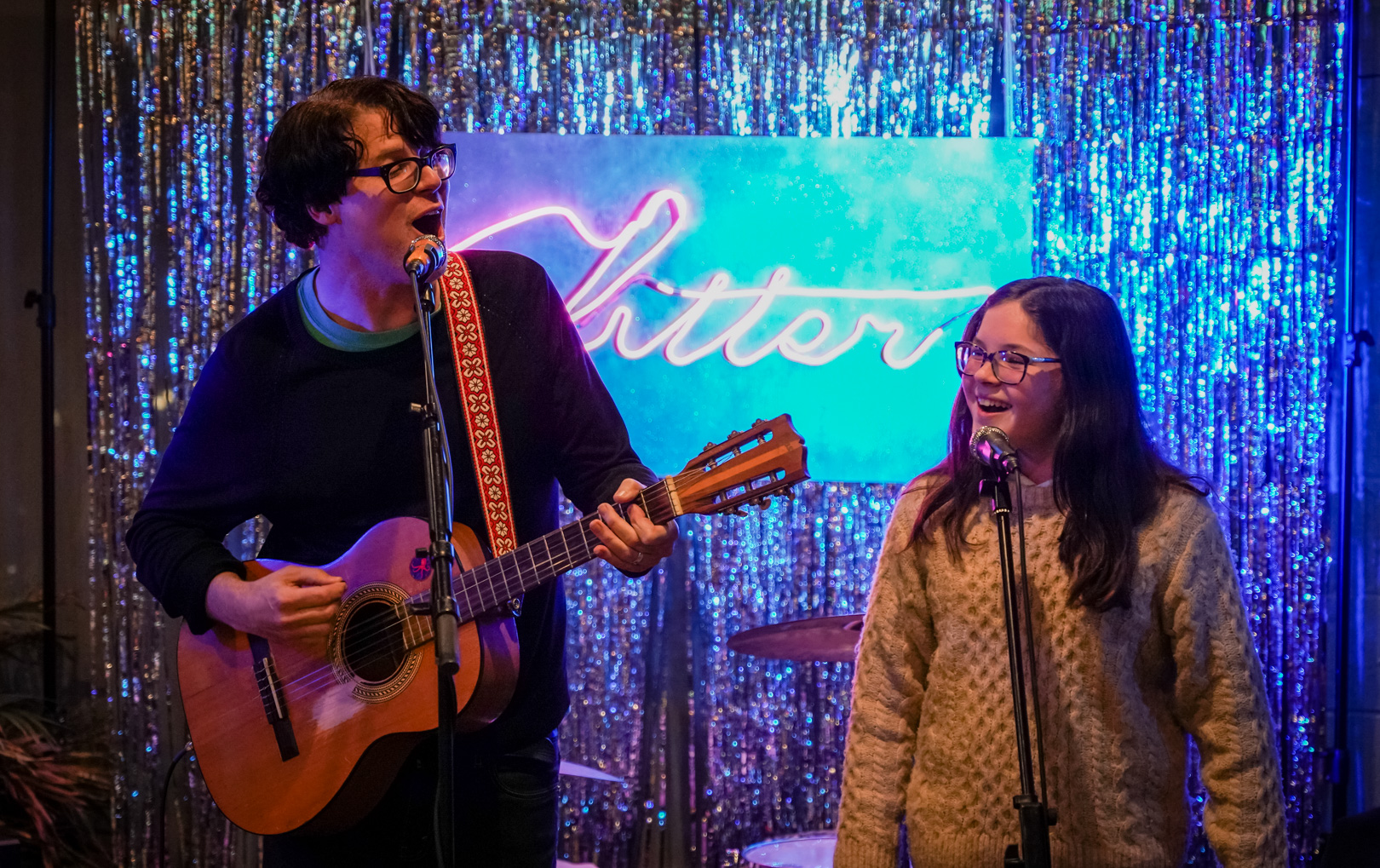 A father and daughter playing music and singing on stage