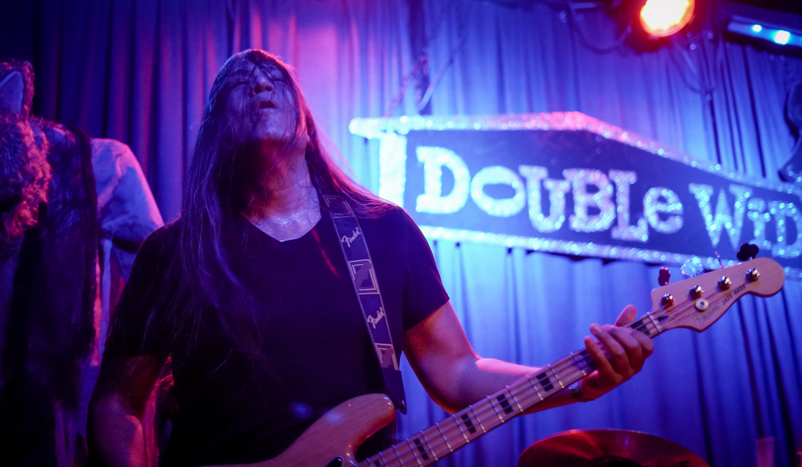 A bassist with long hair on stage