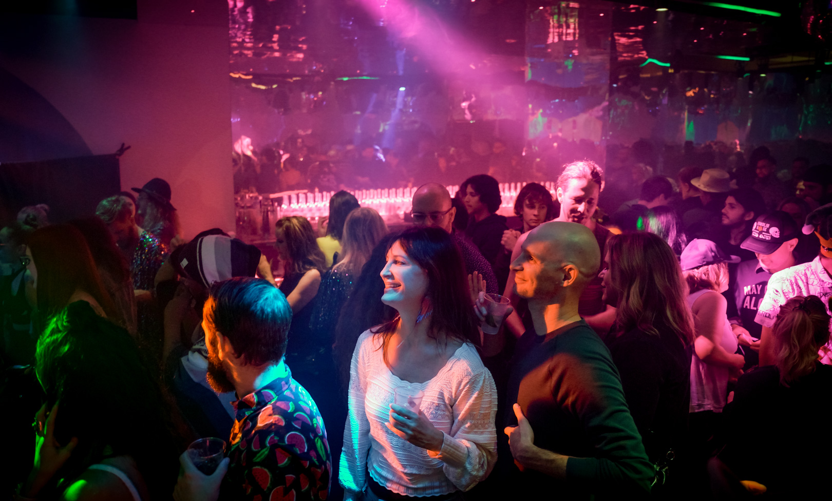 A full crowd dancing in a bar with disco lights