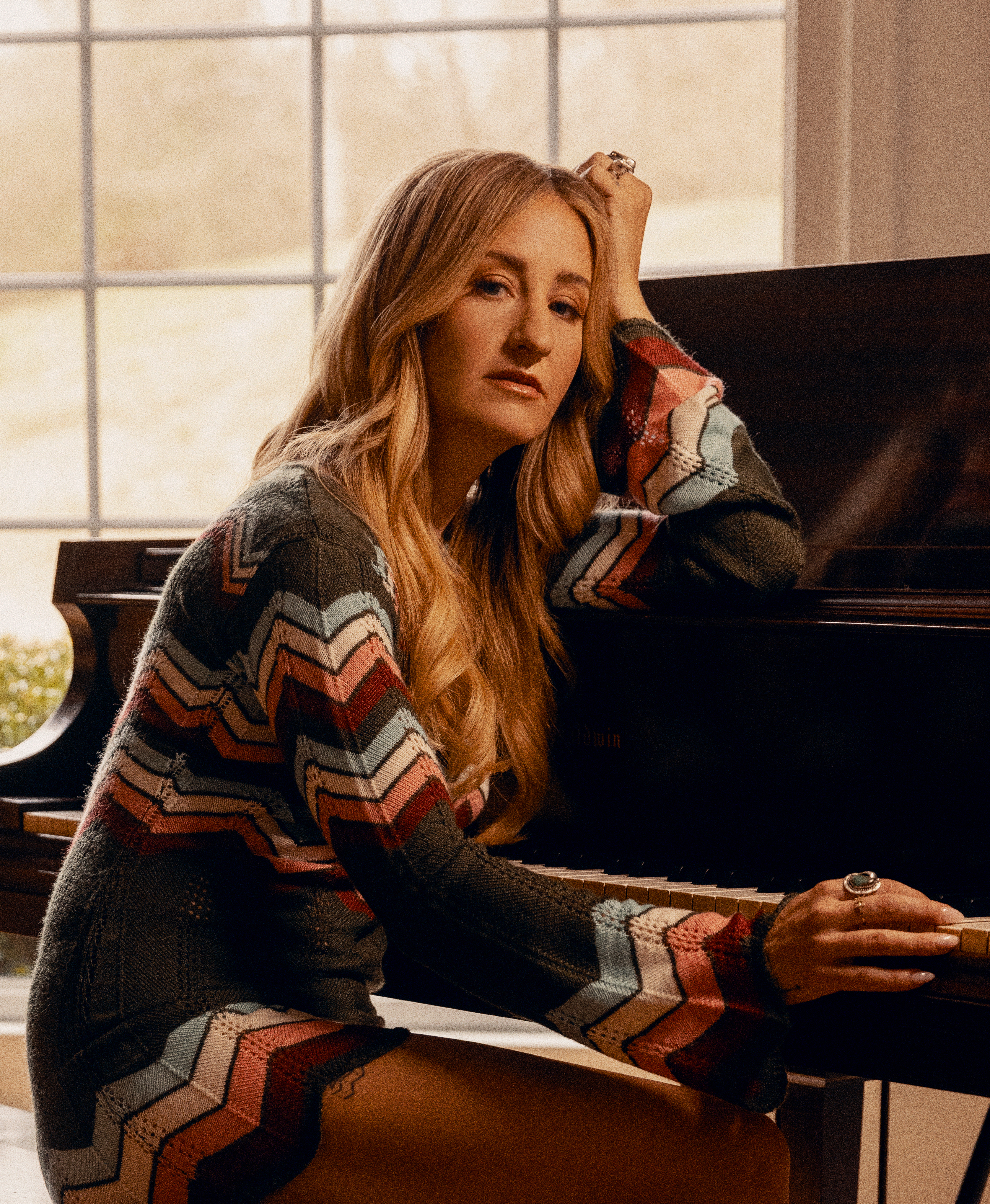 Seated at a piano, Margo Price looks toward the camera