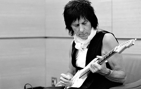 Jeff Beck, wearing a black vest, plays an electric guitar