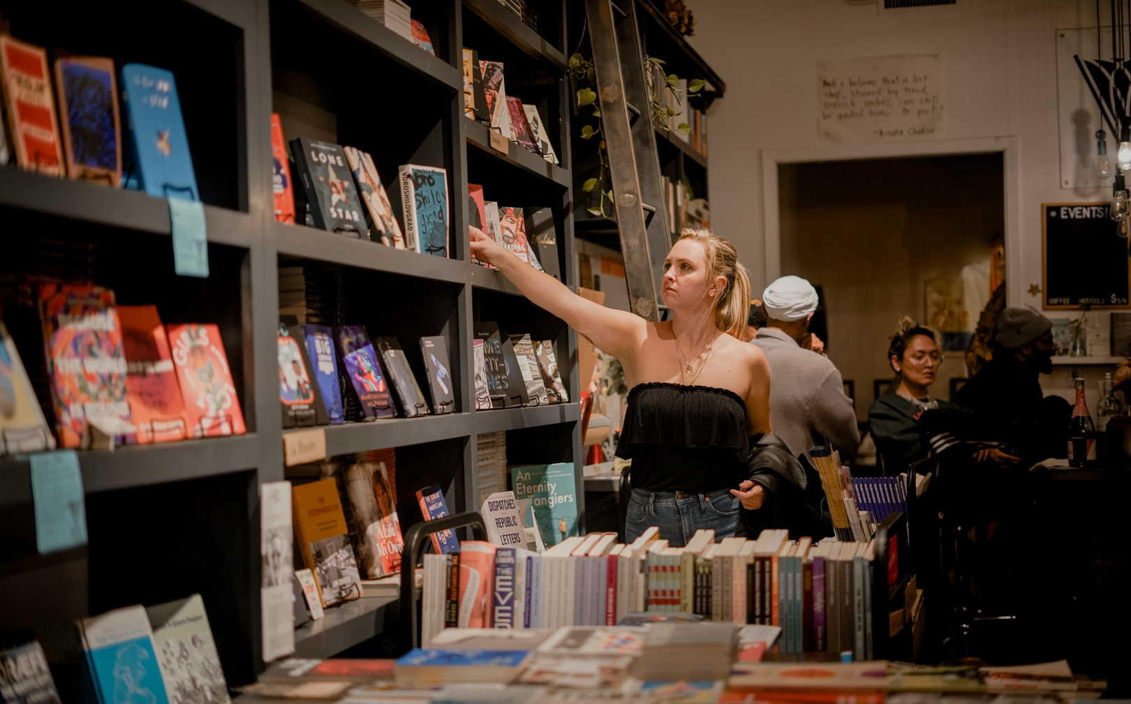 A person browses books on a shelf inside a book store