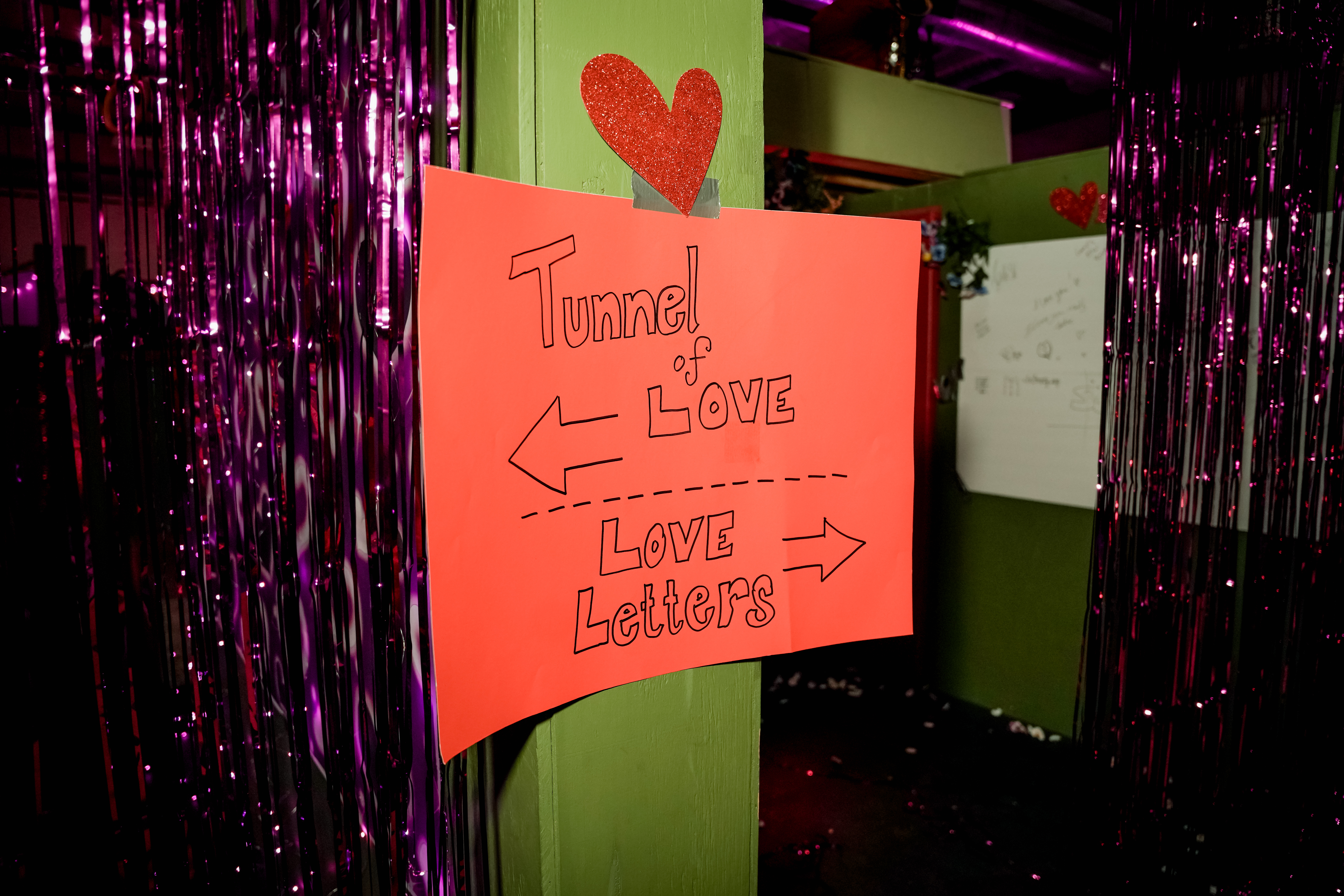 A poster up on a wall that says "tunnel of love" to the left, "love letters" to the right