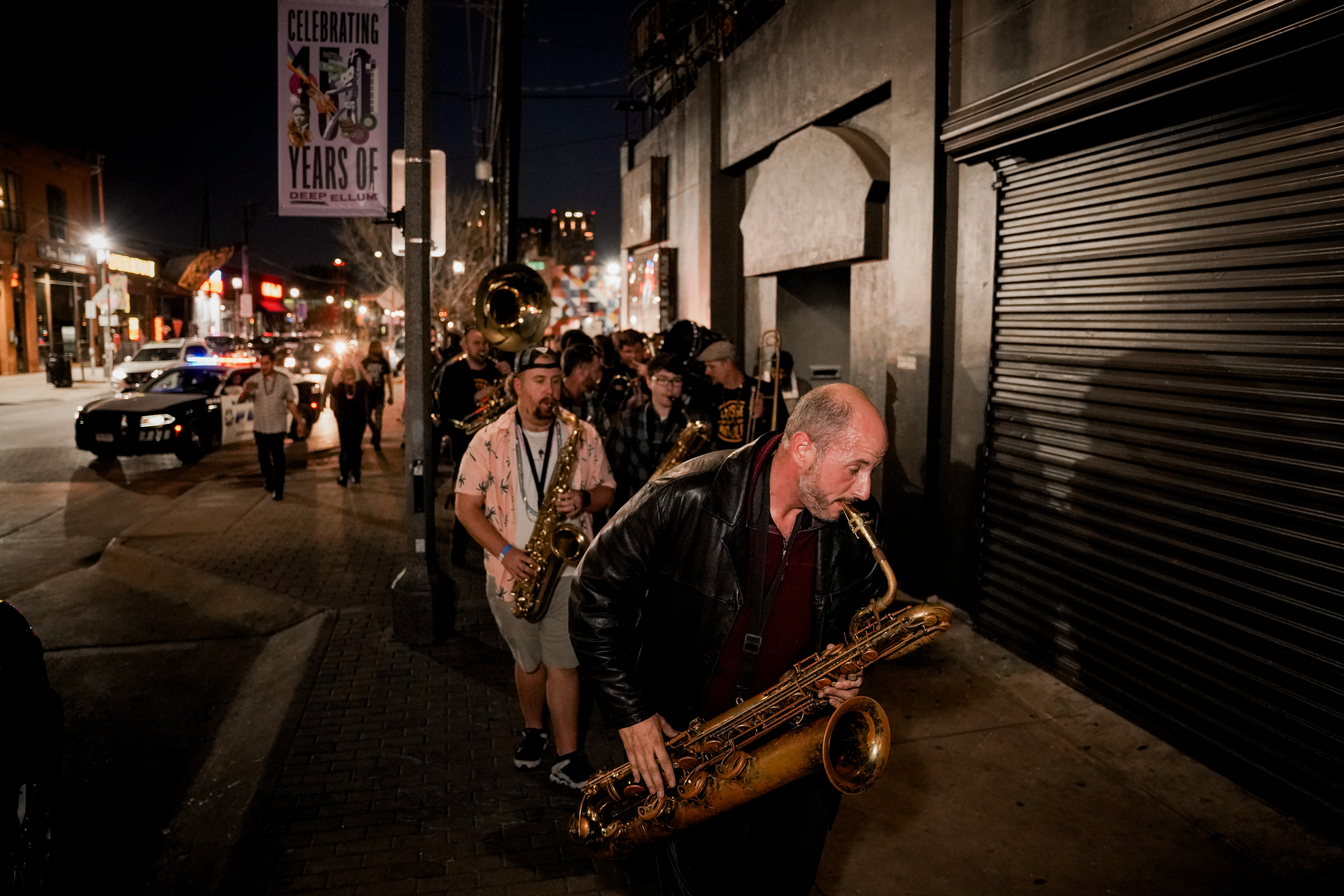 A second line brass band marching down a sidewalk