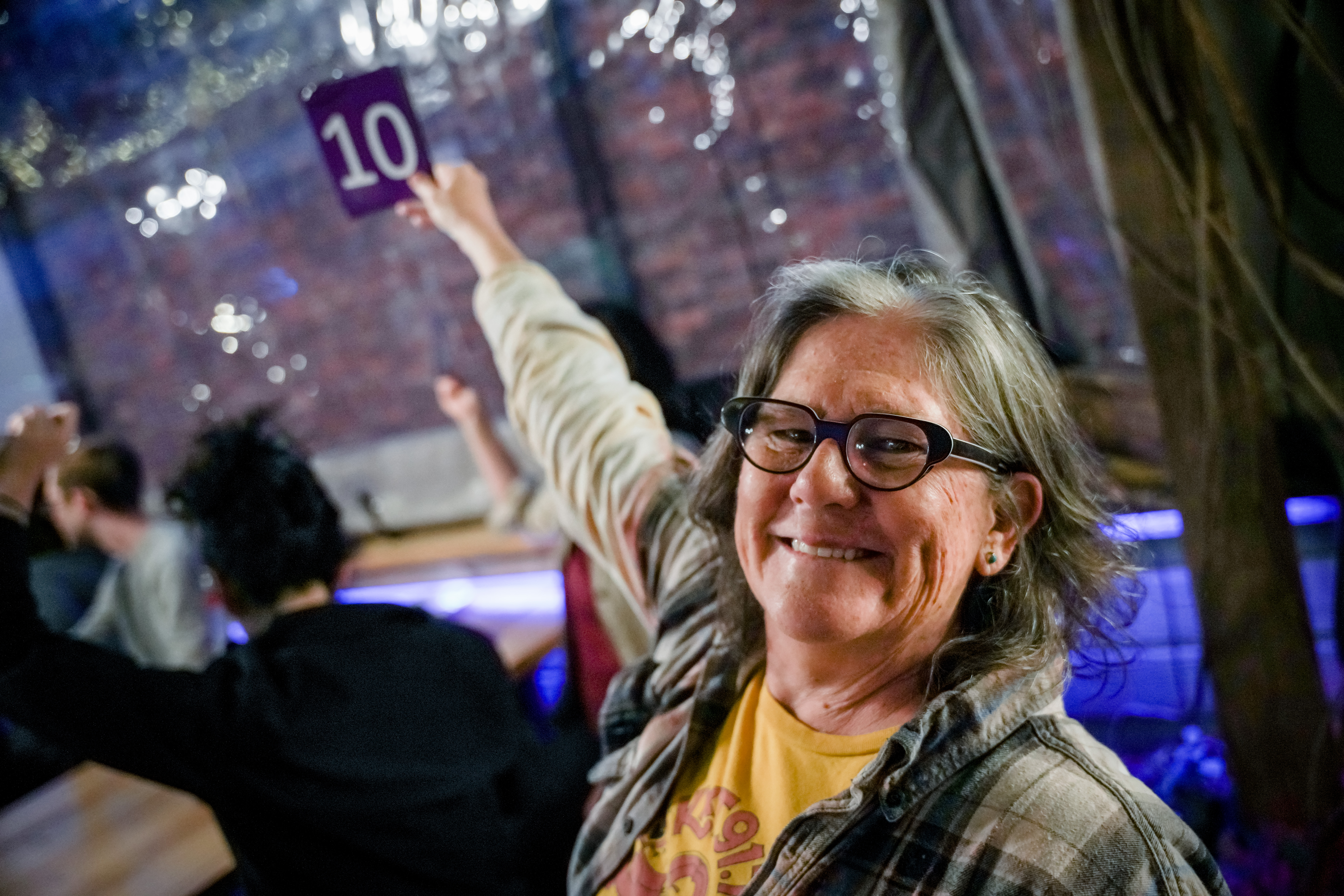 A woman smiling and holing a sign that says 10