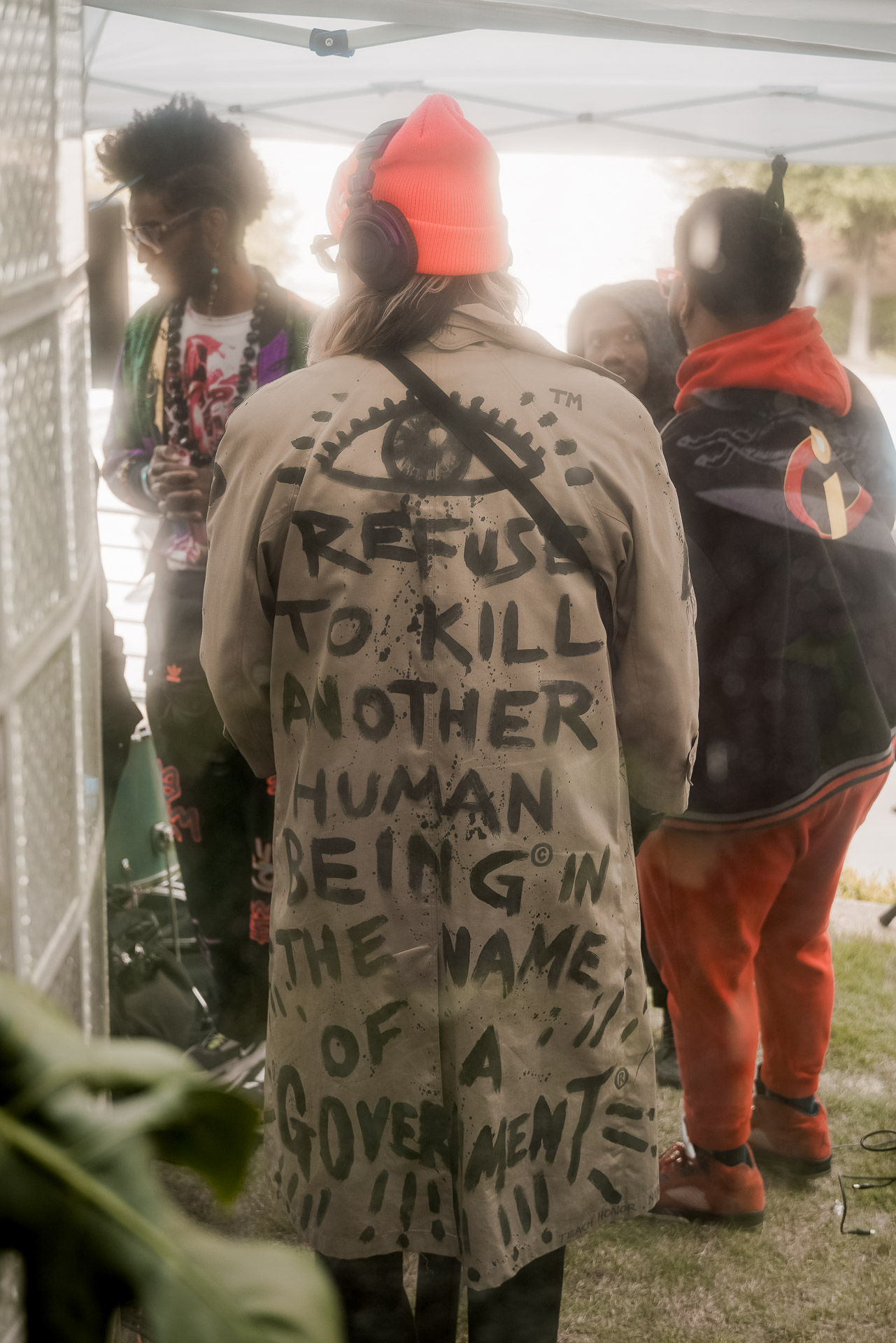 A man wearing a jacket that says "'eye' refuse to kill another human being in the name of a government"