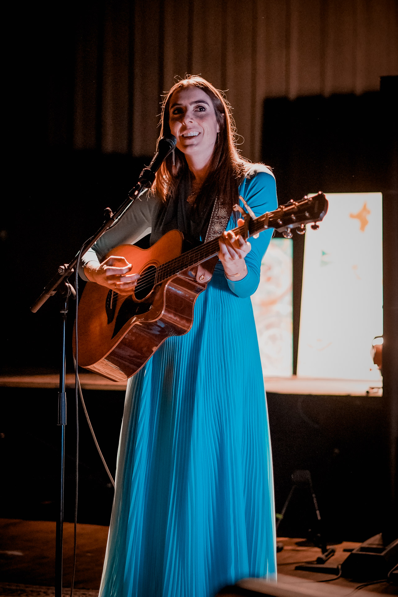 A portrait of a woman singing and playing guitar