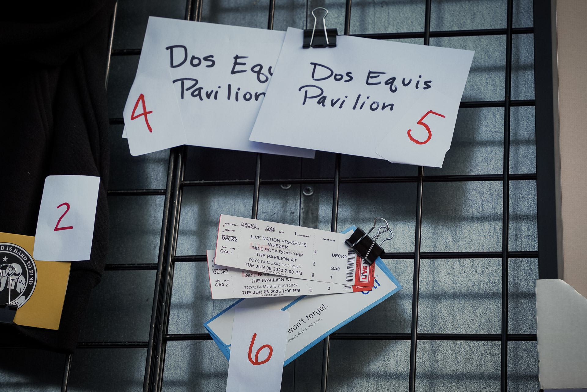 Envelopes that say "Dos Equis Pavilion" and concert tickets on a wall