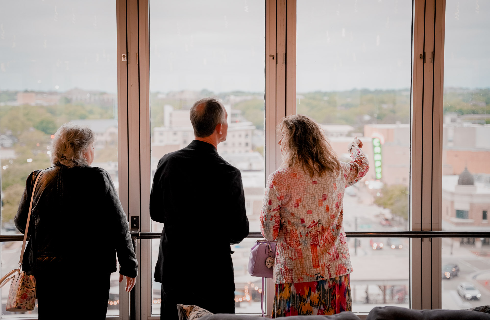 Three people looking out a window over a city
